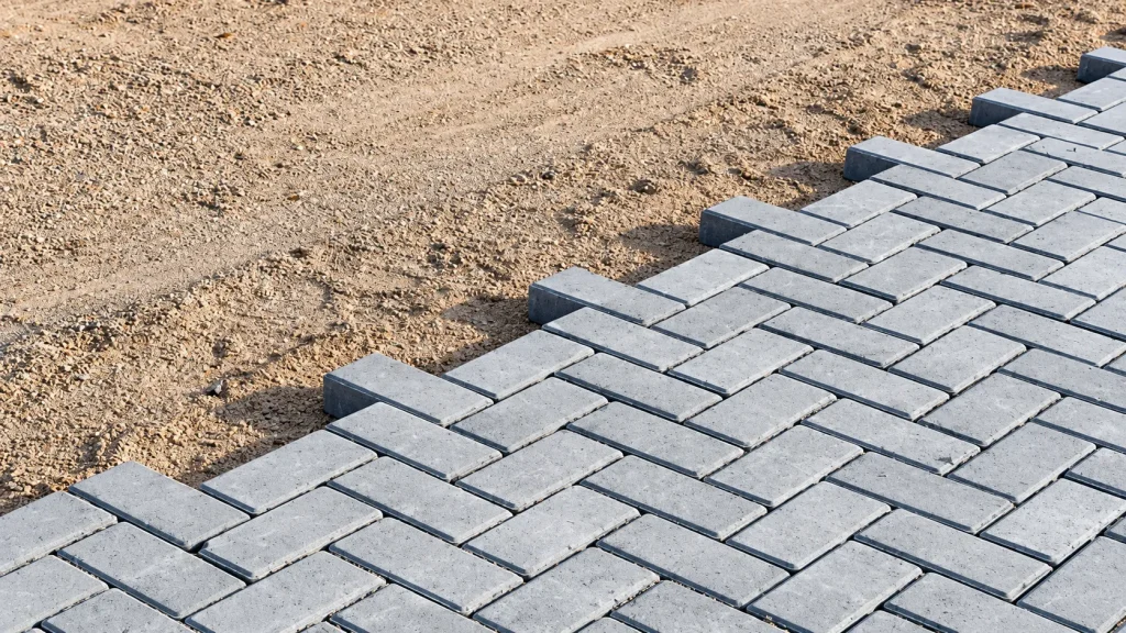Pavers de concreto sendo assentados sobre base de areia